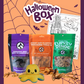 Halloween-themed pet product box with treats and a toy on an orange background.